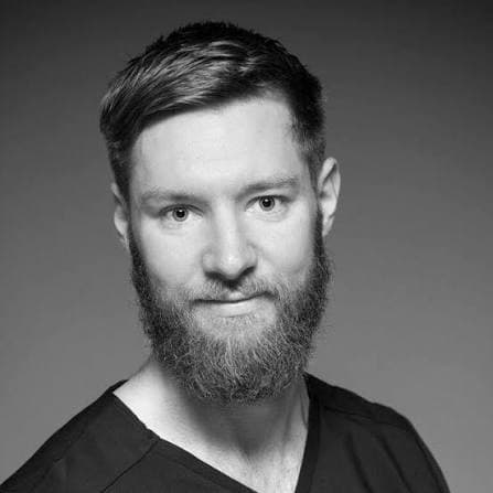 Black and white headshot of a man with a full beard and short, styled hair.